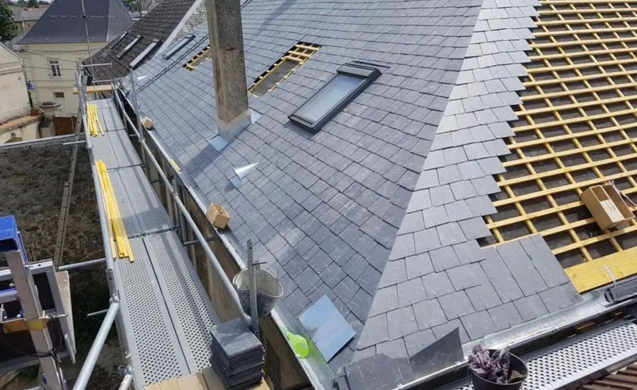 Couverture en ardoise sous échafaudage à Mont-Saint-Aignan, avec une fenêtre de toit et une souche de cheminée à solin en zinc